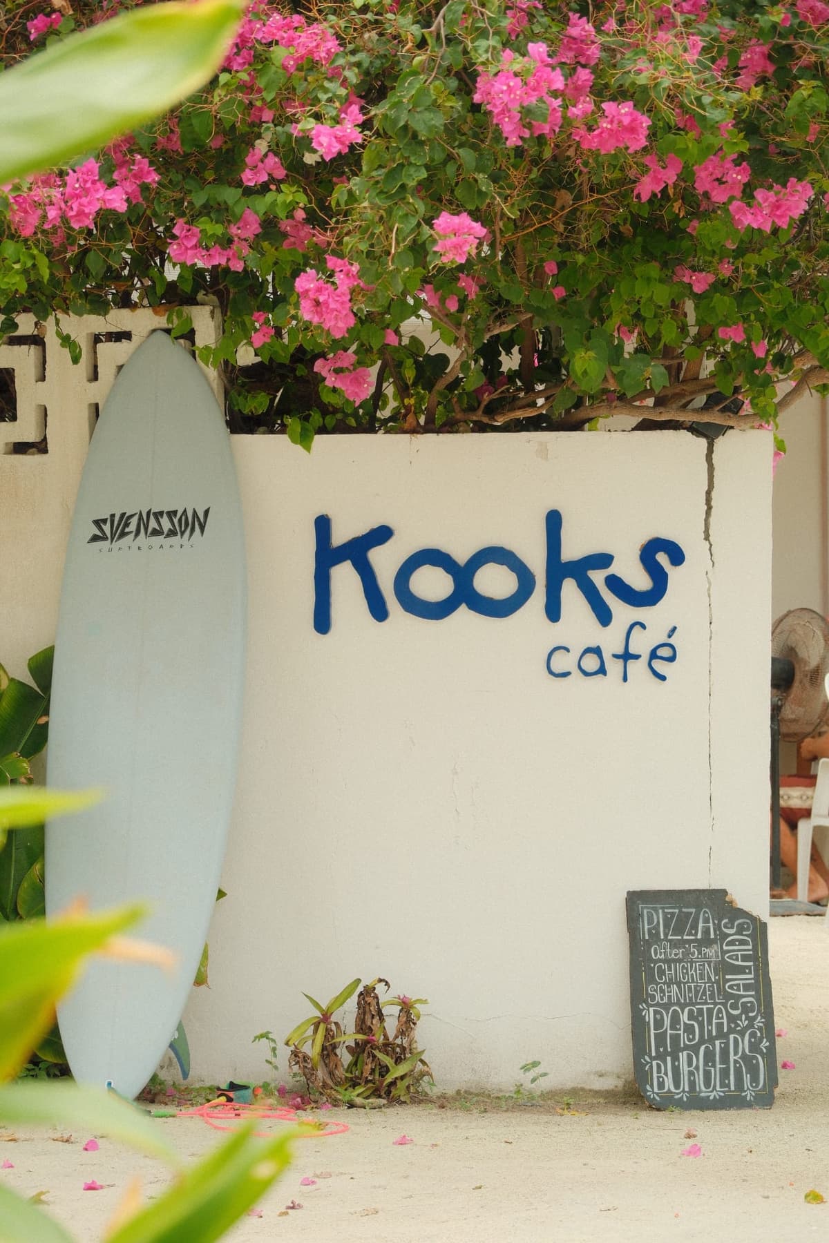 Surf shop charm — bougainvillea, board, and chalk menu