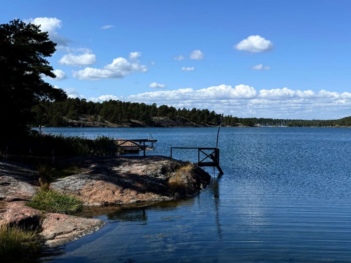A wooden jetty off the granite, the bay flat and blue under high summer clouds