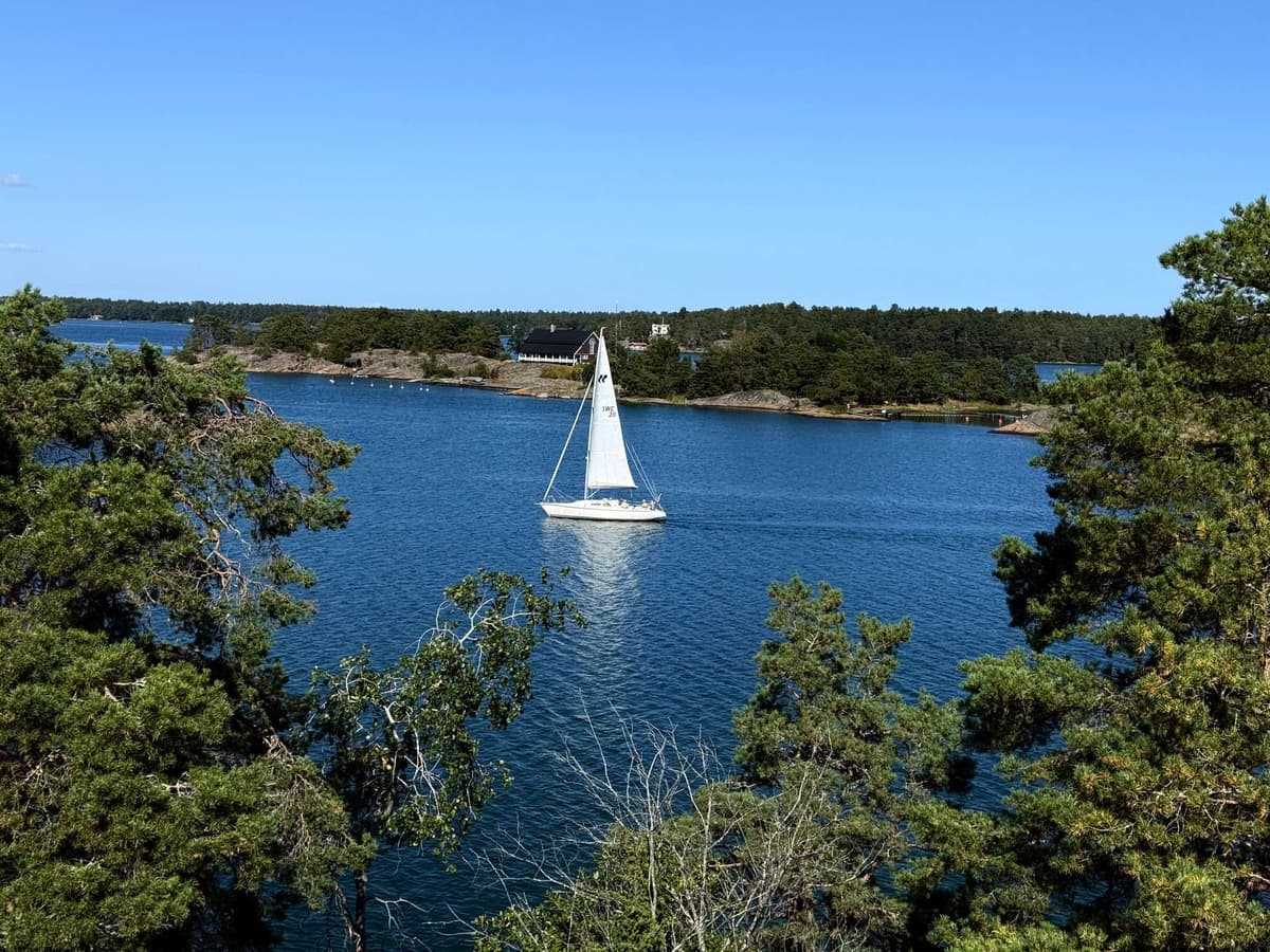 One white sail crossing the bay, islands stacked to the horizon