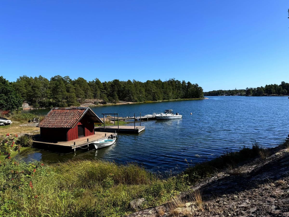 A red boathouse and its jetty, the boat pulled up alongside