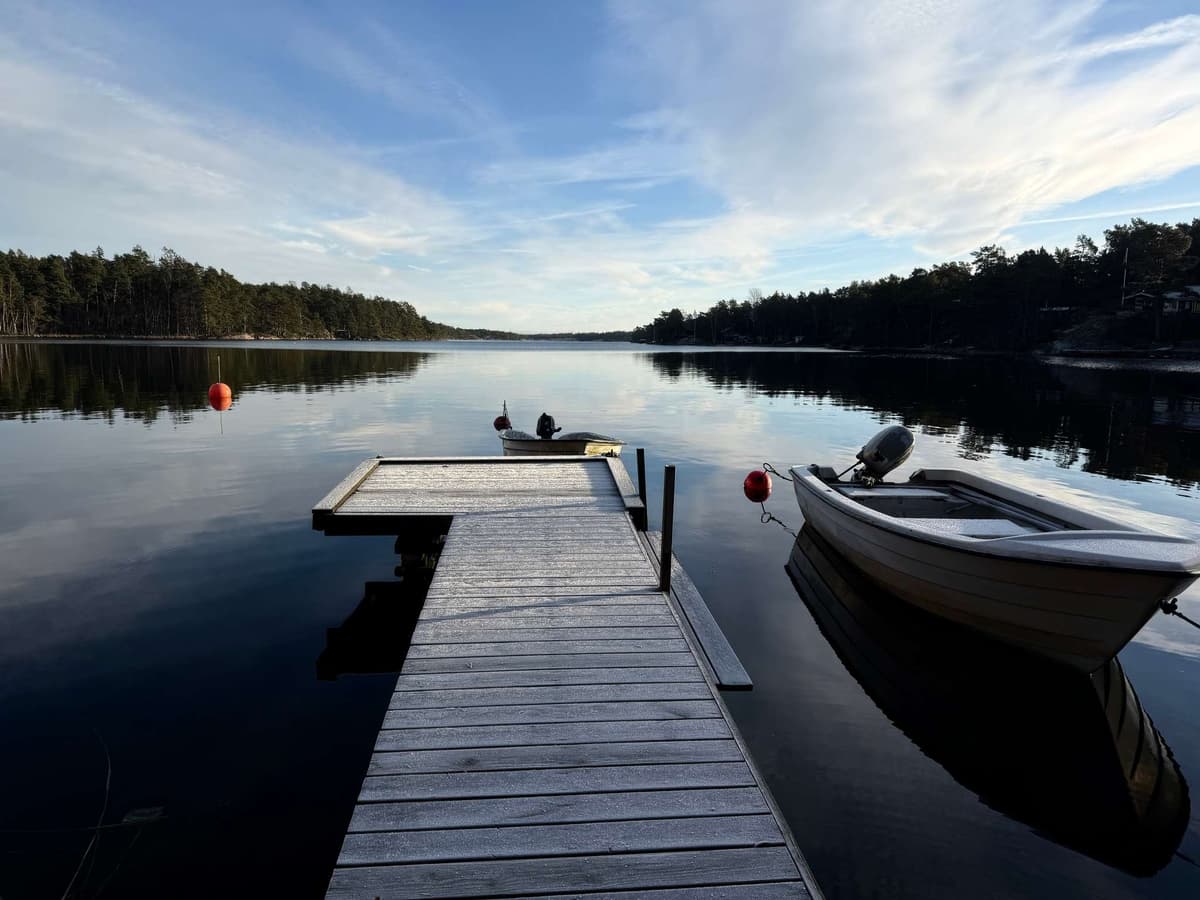 A jetty and an outboard boat on mirror-still winter water