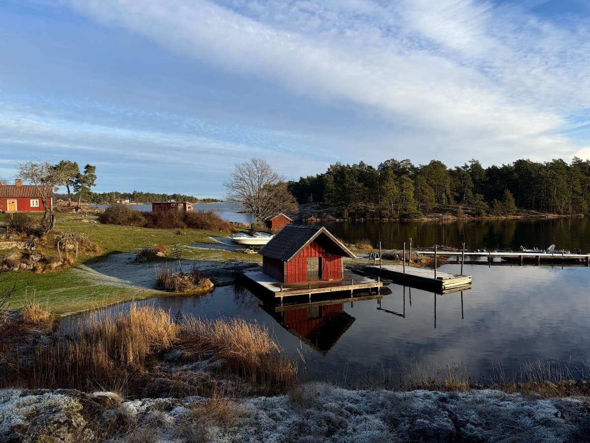 The red boathouse from across the inlet, reeds gone the color of straw
